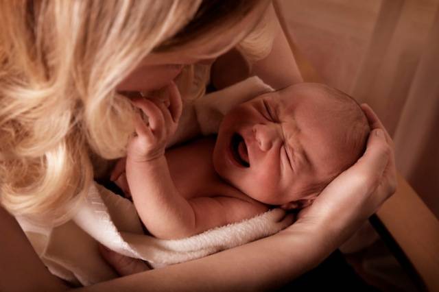 Bimbo che piange in braccio alla mamma.